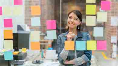 Una mujer mirando post-its en una pizarra de borrado en seco.