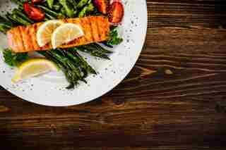 Salmón a la plancha con espárragos y rúcula sobre mesa de madera