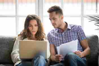 Una pareja que parece preocupada por el dinero, con una computadora portátil y facturas.