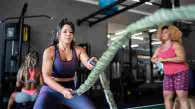 Mujer usando cuerdas de batalla en el gimnasio.