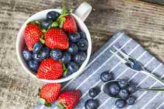 Fresas y arándanos en una taza blanca