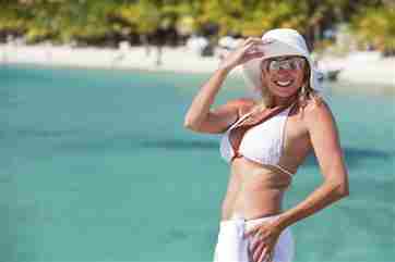 Mujer en la playa en bikini y sombrero para el sol