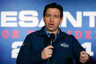 Proporcionado por Al Jazeera El gobernador Ron DeSantis habla por un micrófono frente a una pantalla que muestra el logotipo de su campaña presidencial.