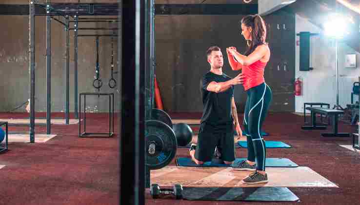 Instructor de fitness enseñando a la persona a ejercitar la postura en el gimnasio