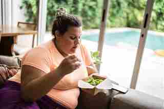 Mujer adulta media comiendo ensalada en casa