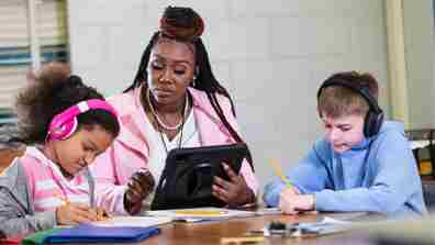 Kali9 / E+ vía Getty Images Un maestro que usa una tableta para educar a dos estudiantes pequeños.
