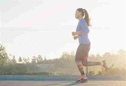 Proporcionado por Autoridad Orgánica Imagen de una mujer con ropa deportiva corriendo al costado de una carretera con una cerca de tela metálica y árboles al fondo.